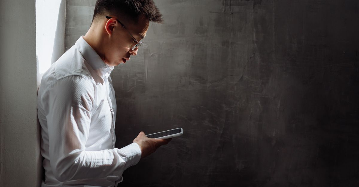 Pria menggunakan smartphone untuk mencari lowongan kerja